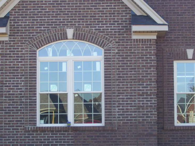 The same wall on the day of the work, the joints around the arched window now stained dark and reading close to the brick