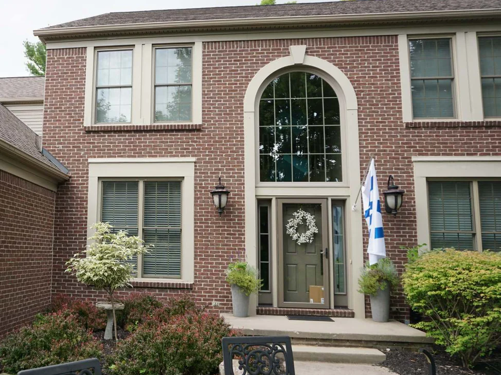 The front entrance of the two-story house in 2019, red brick running evenly around a tall arched window over the door