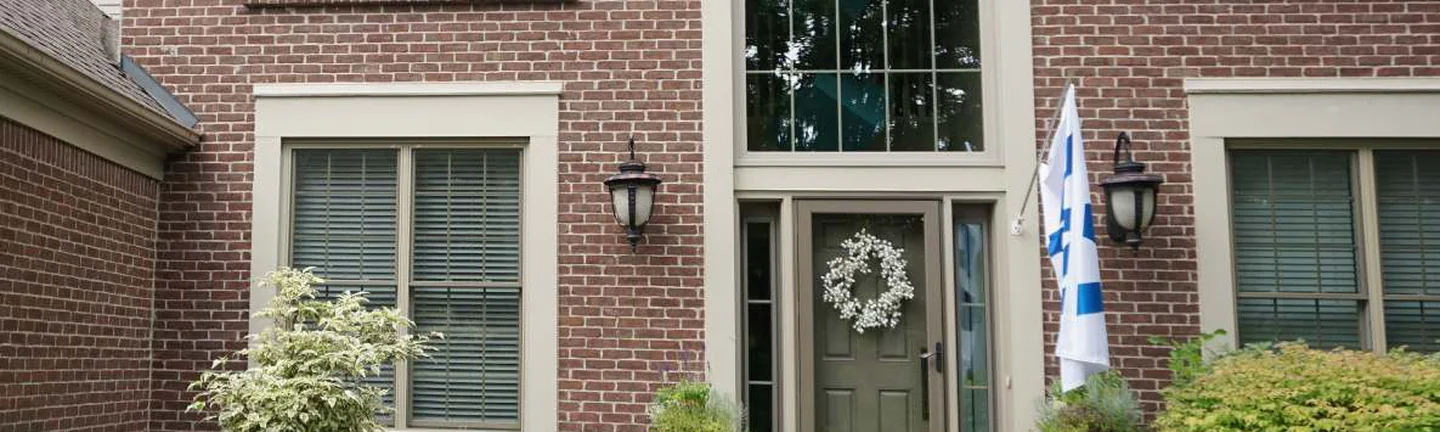 The brick front of the Lake Orion house in 2019, an arched window over the entry and one even red range across the wall