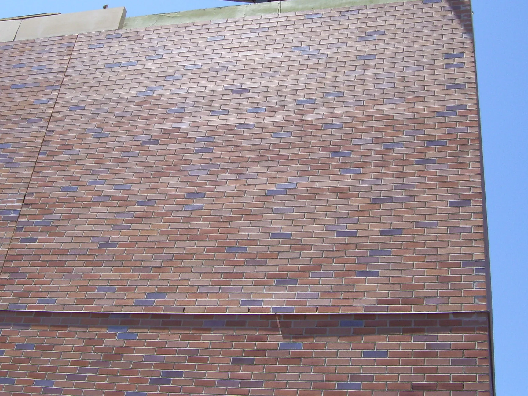 The top of the hospital's brick wall during the 2007 work, seen from the ground against open sky, with darker units scattered through the range below the coping