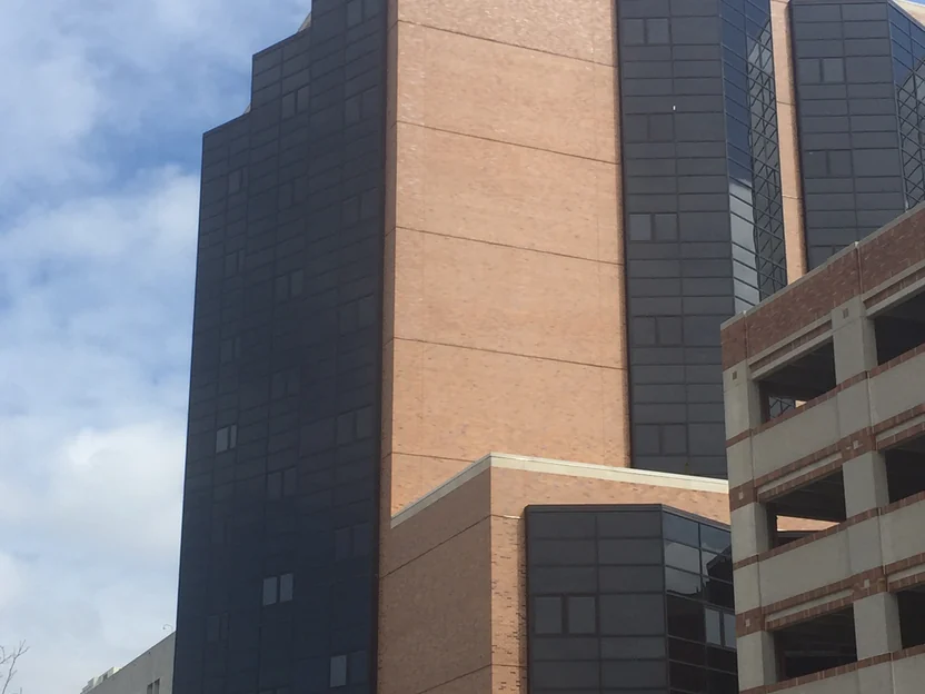 The hospital tower in 2016, its brick piers running the full height of the building between bays of dark glass
