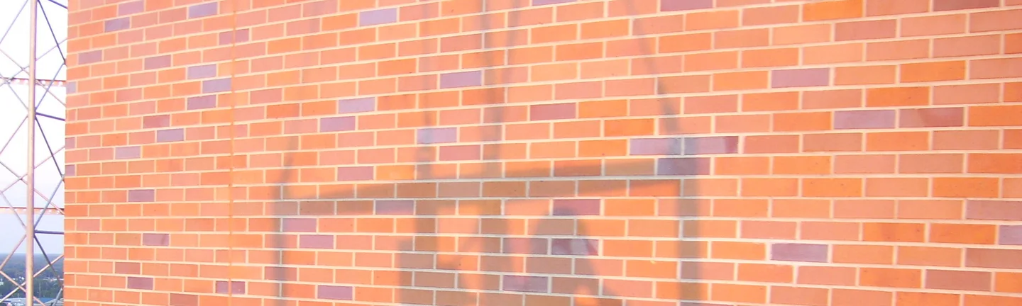 A high brick wall on the hospital in 2007 with the work finished, light units blended into the red and purple range around them