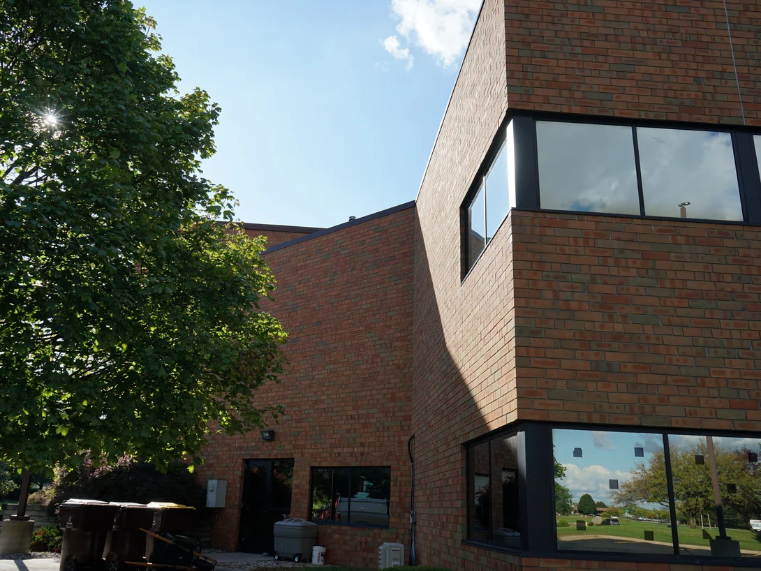 The projecting corner bay of the office in 2019, the brick evenly ranged on both faces beneath a dark window band