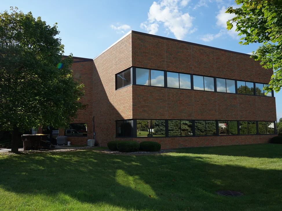 The office seen from across its front lawn in 2019, the brick reading as one red and orange range across both storeys.