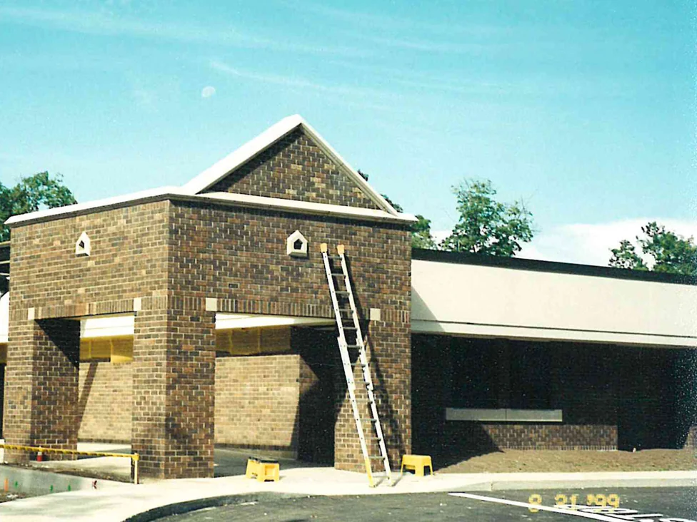 A ladder standing against the school's new brick entrance canopy, the brick range running from dark brown to near cream