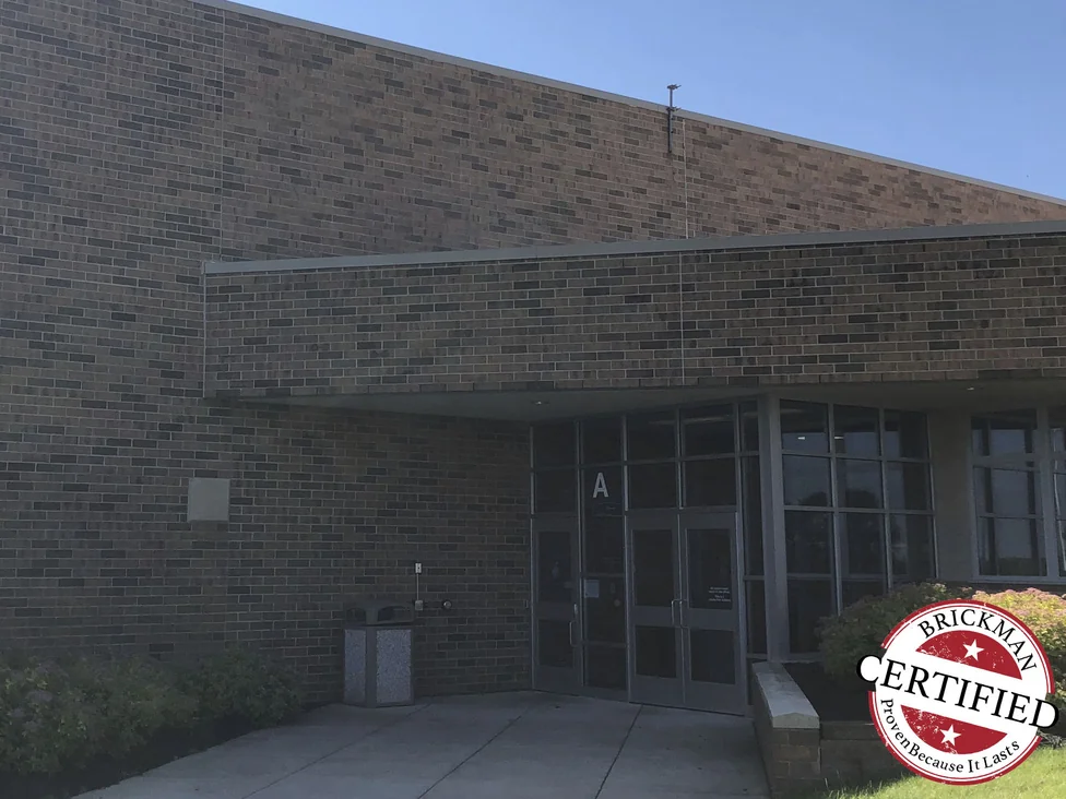The school entrance in 2019 with the Brickman certified stamp across the corner of the frame, the brick an even mix of browns, greys and reds