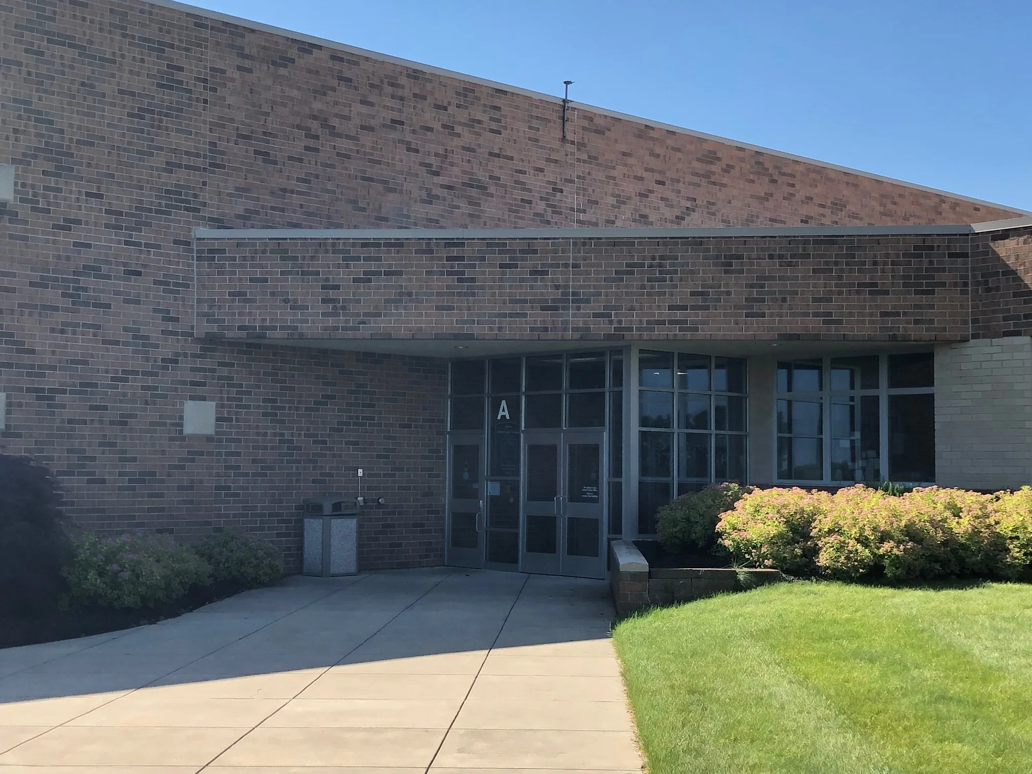The school's A entrance in 2019, individual brick units reading brown, grey and red across the wall, with a pale buff brick return at the right edge