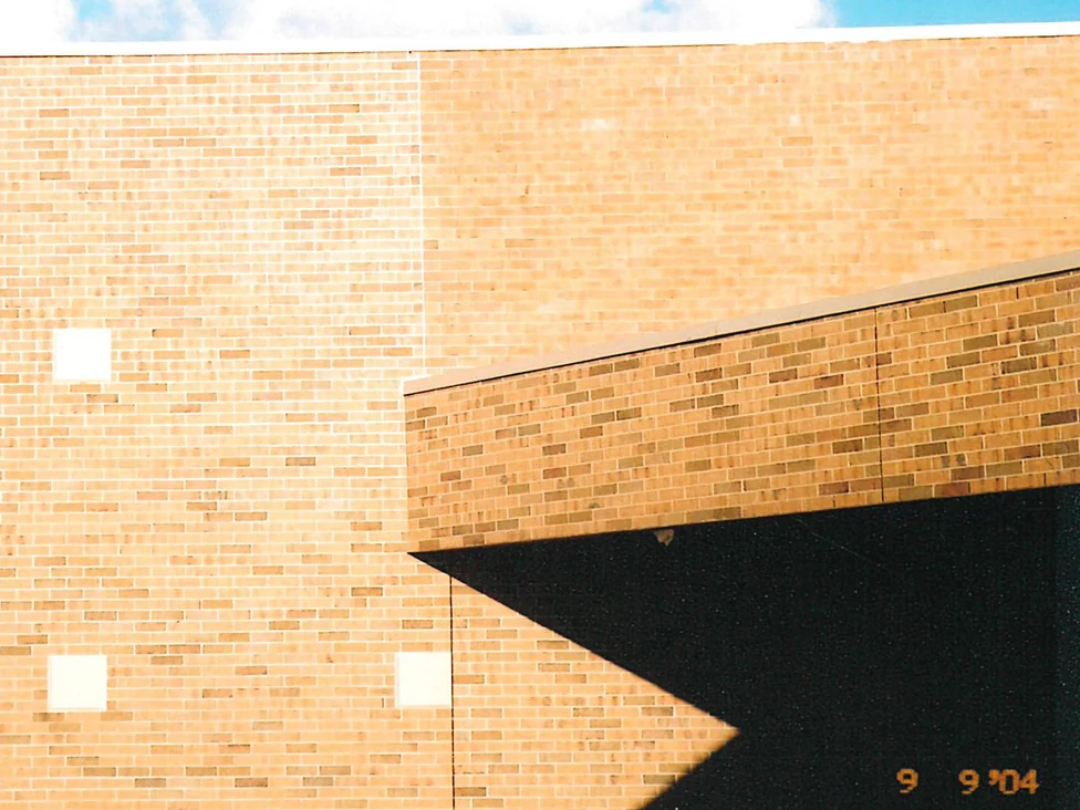 A school wall in 2004, the flat pale brick left of a vertical joint sitting against warmer, more varied brick to the right of it