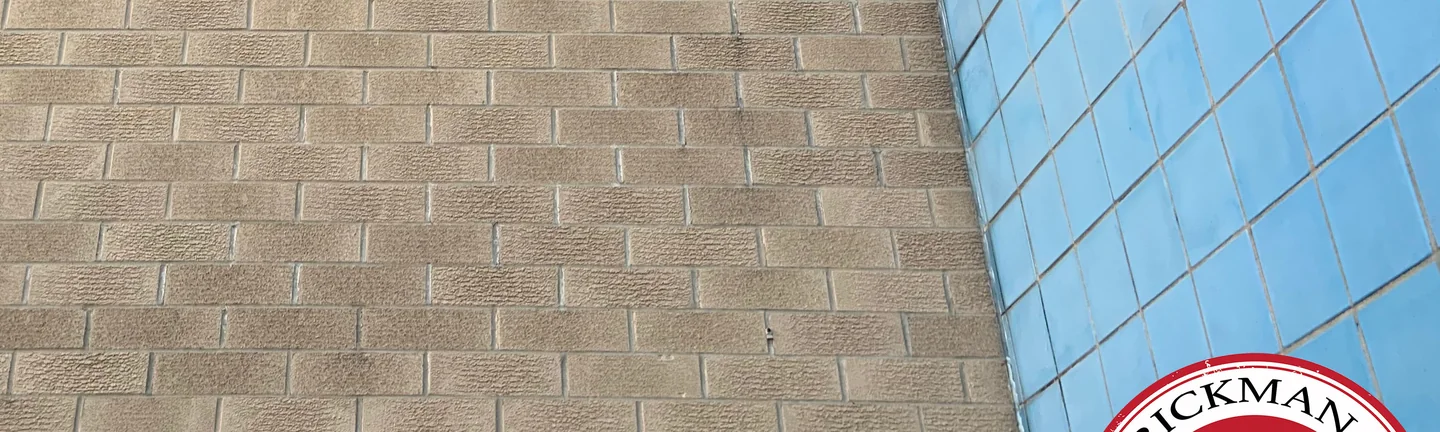 The buff brick wall of the Lima office building in 2019, one even range of tan units beside the blue glazed tile of the entrance tower