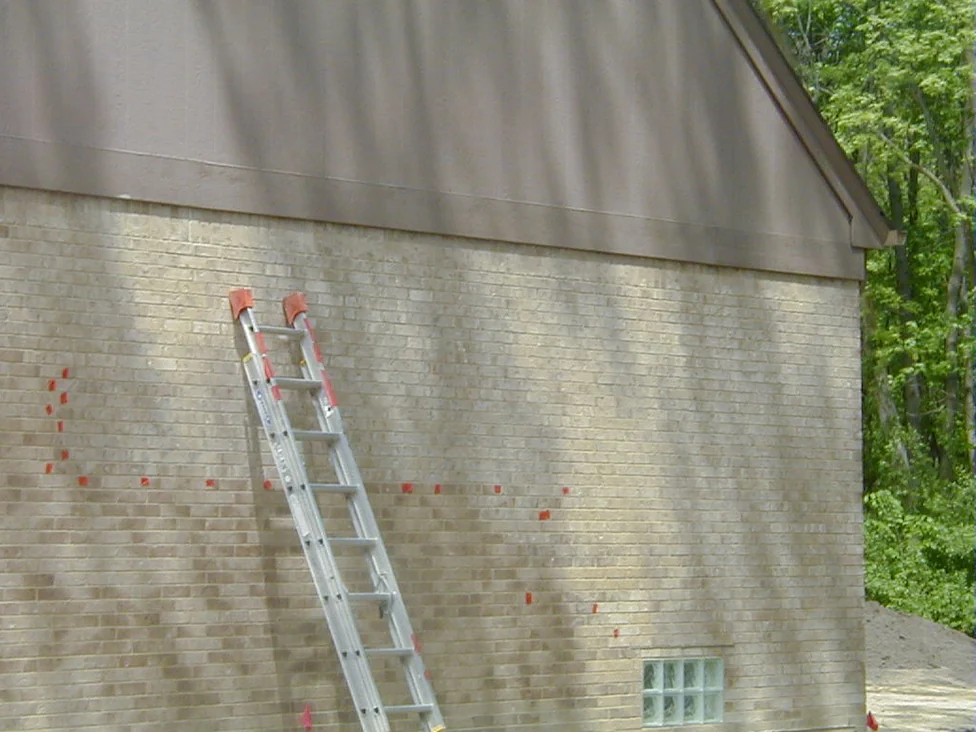 The gable end of the house in 2005, a ladder leaning against the brick and small orange marks dotted across the wall