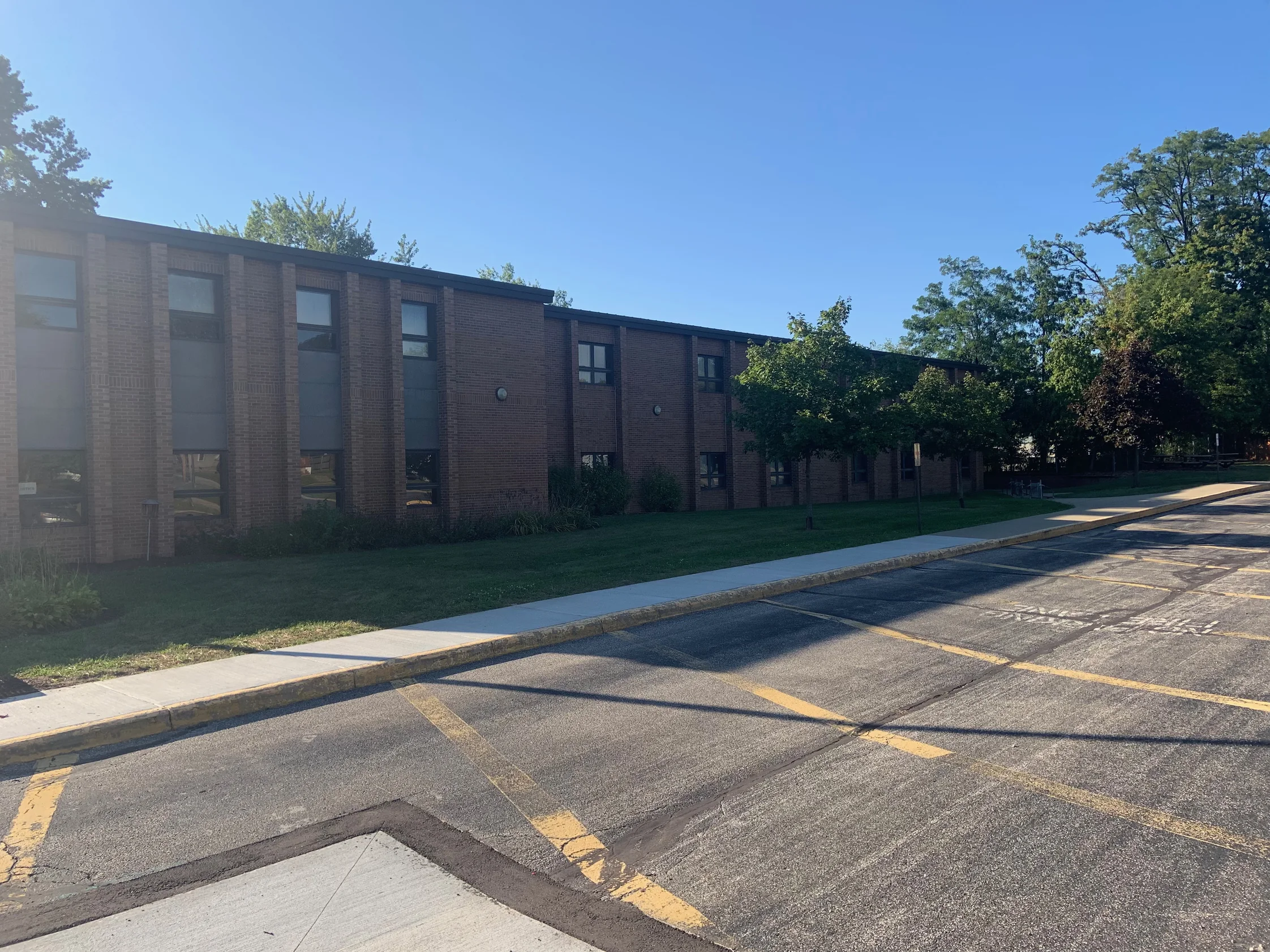 The long two-story classroom elevation seen from the parking lot in 2019, the brick reading as one mixed red and brown range the length of the wall