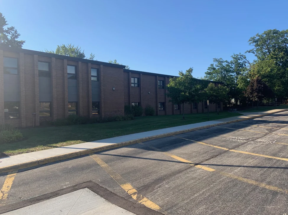 The long two-story classroom elevation of the school seen from the parking lot in 2019, the brick reading as one mixed red and brown range the length of the wall.