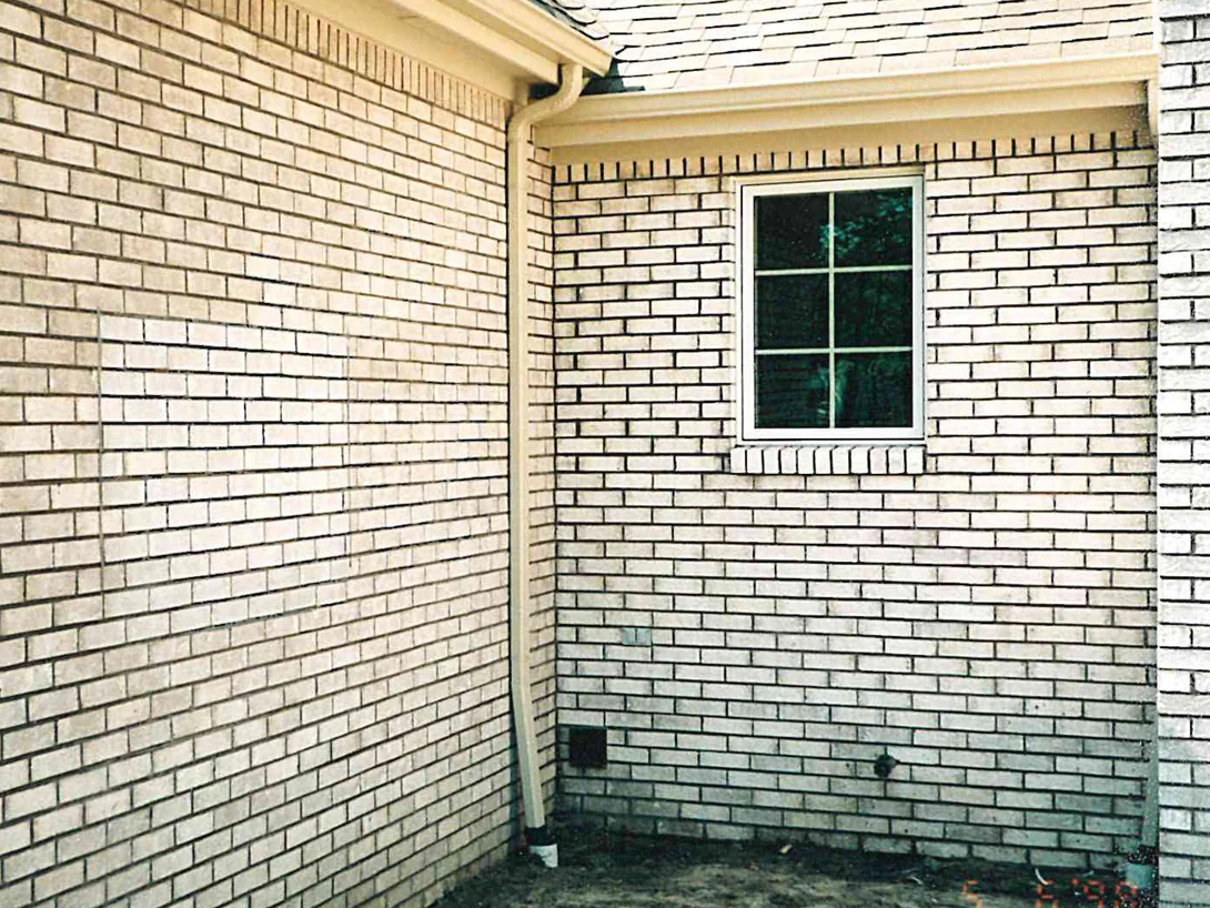An inside corner of the house in 1998 at a downspout, the brick a mixed range of cream and darker tan units under a small window, with a camera date stamp in the corner