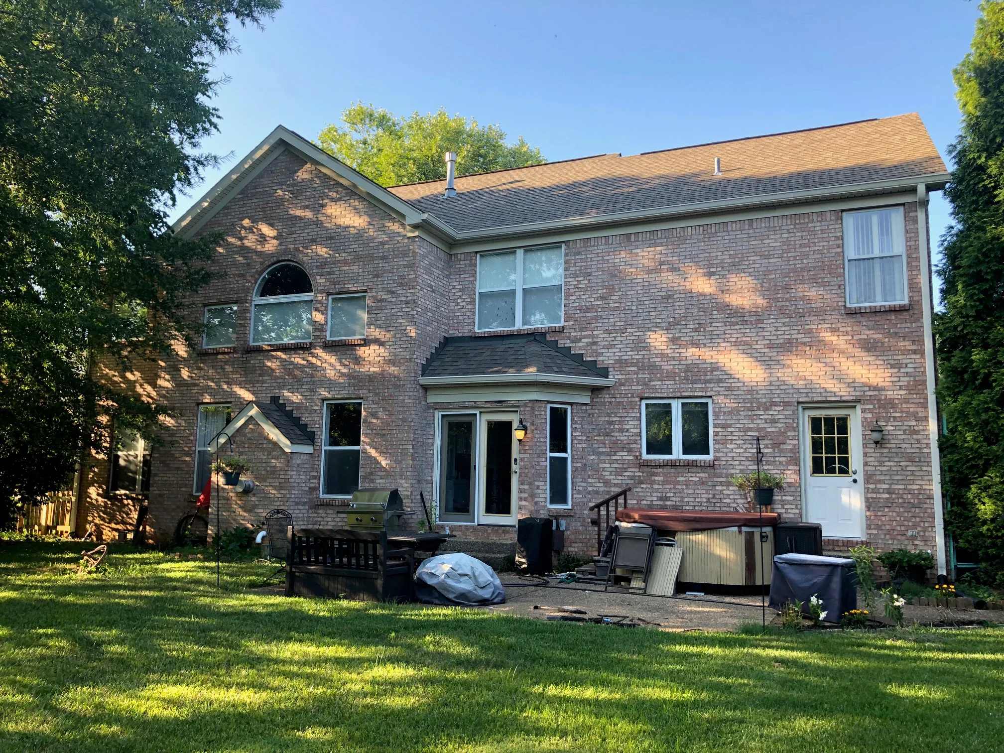 The rear of the house in 2019 across the back lawn, two storeys of blended brick running the whole elevation above a patio