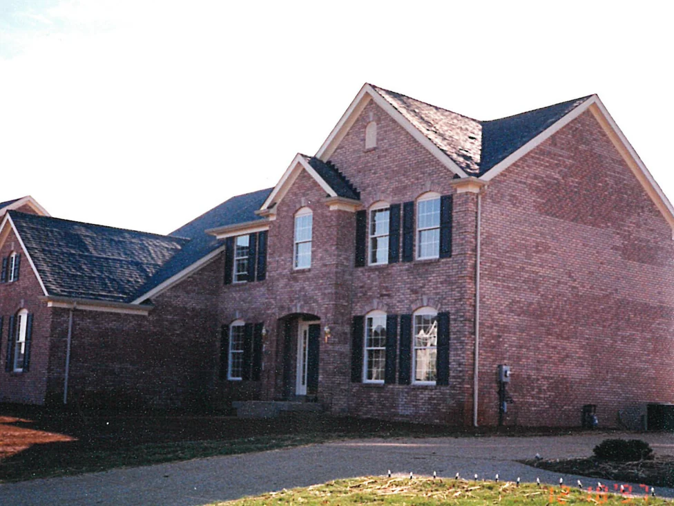 The house from the driveway in 1997 before any work, its brick a dark red brown broken up by paler blotches across the gable end