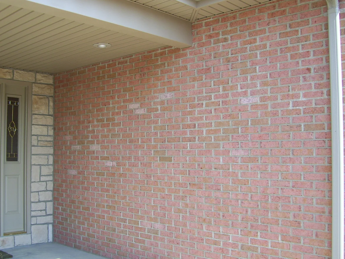 The covered entrance wall in 2007, pale cream units scattered through a range of pink and tan brick beside a stone door surround