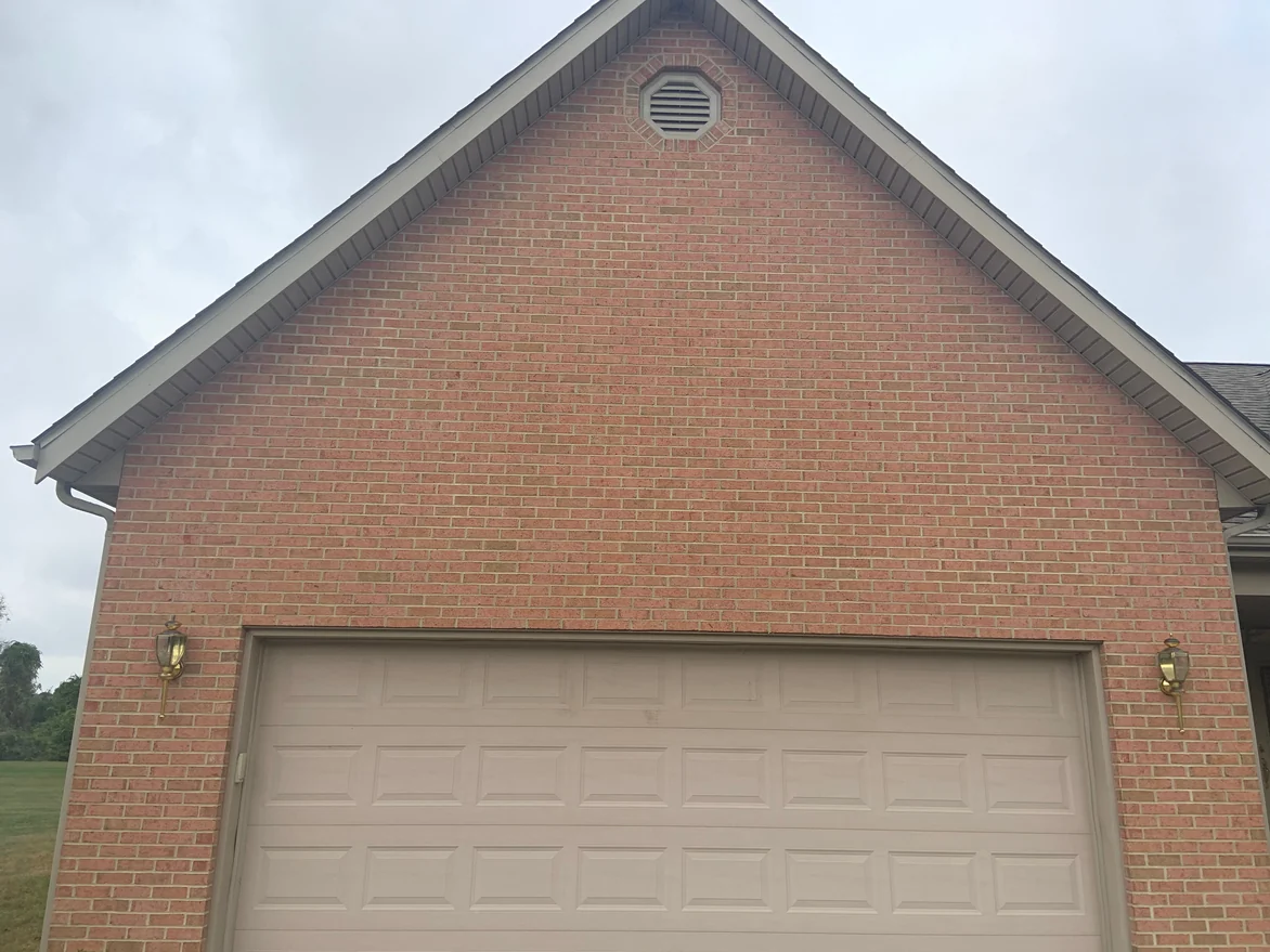 The garage gable in 2019 seen square on, brick courses running up to an octagonal vent at the peak with no light units breaking the range