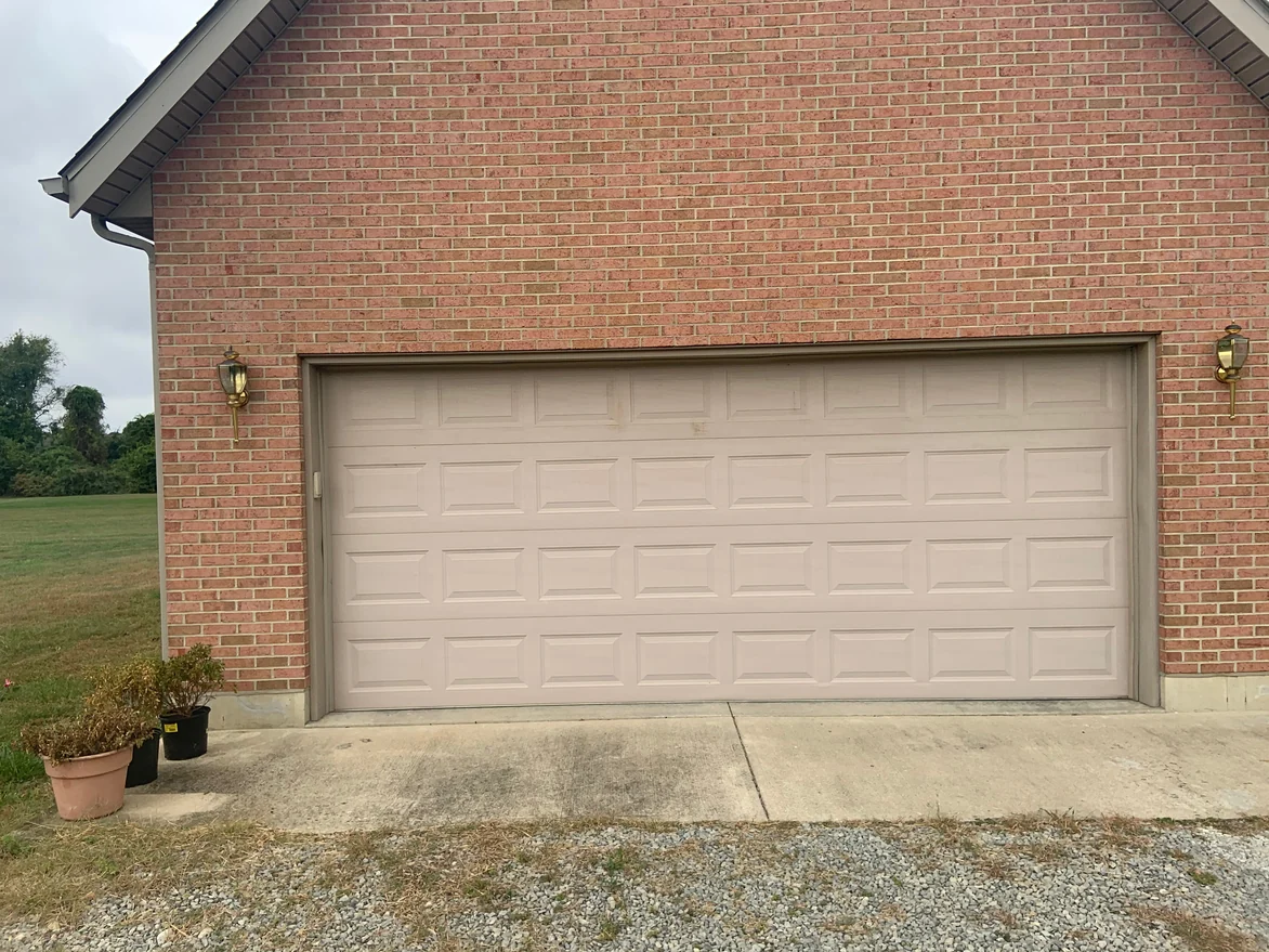 The garage bay in 2019, brick above and either side of the door reading as one range between two carriage lamps