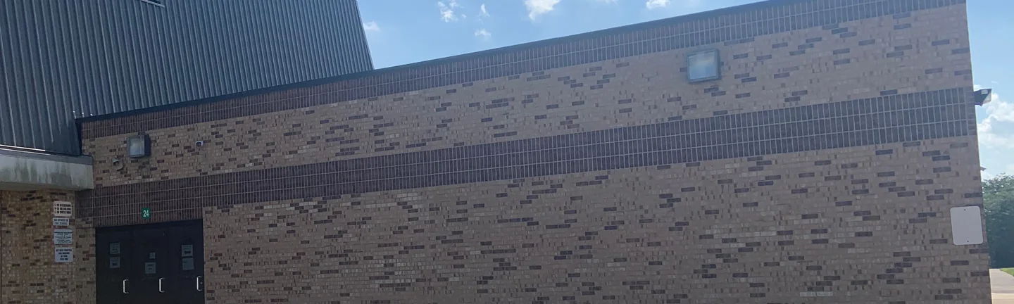A low brick wing of the school in Lynn in 2019, one dark band running the length of the buff brick wall