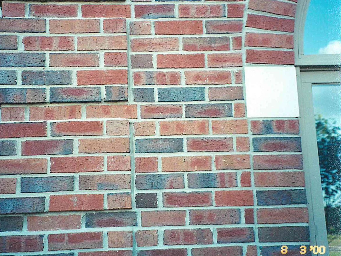 Brick at unit scale in 2000 beside an arched opening, bright red units set among dark blue grey ones in an uneven wall