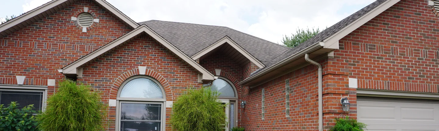 The front of a single-story red brick house in 2019, the brick one even range across both gables