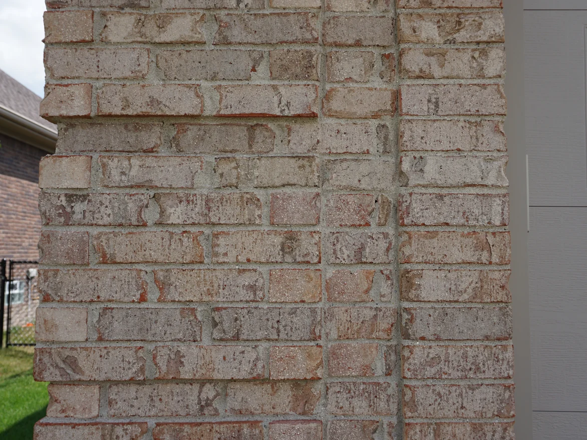 Close view of a brick pier beside the garage, the units in mixed creams, greys and soft reds with pale mortar joints