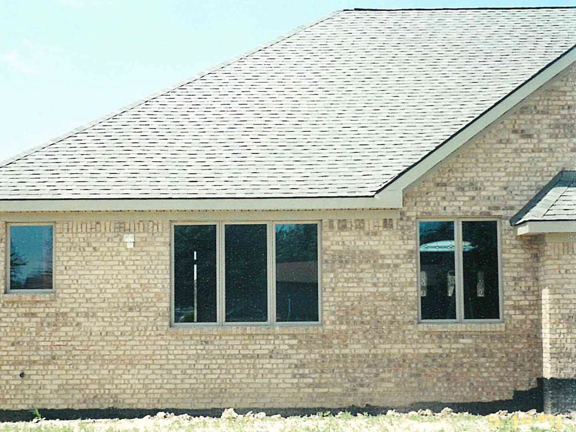 The side elevation of the same house, a long run of cream and buff brick under a low hipped roof