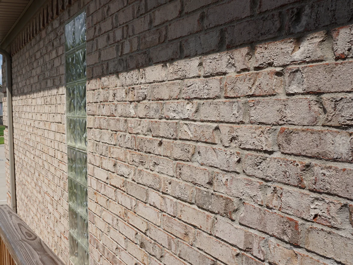 An oblique view along the blended wall past a glass block window, the brick reading as one range of cream and grey
