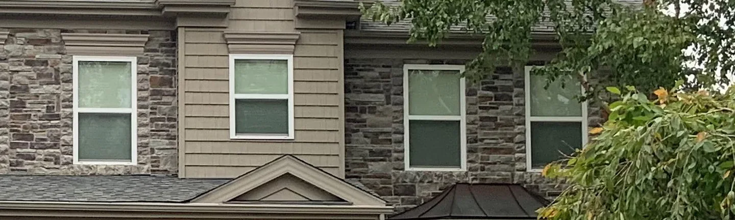 The upper floor of the manufactured stone house in 2020, grey window sills sitting inside the grey and brown stone blend