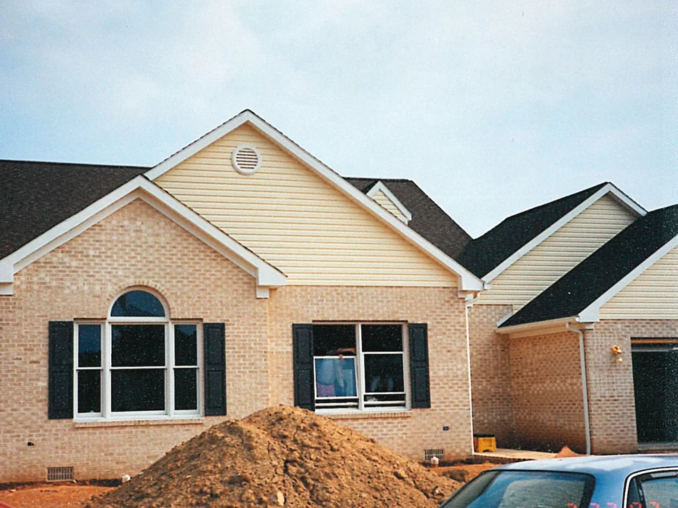 The front of the house in 1997, its brick a pale peach and cream mix that changes from unit to unit, with bare earth still heaped against the wall