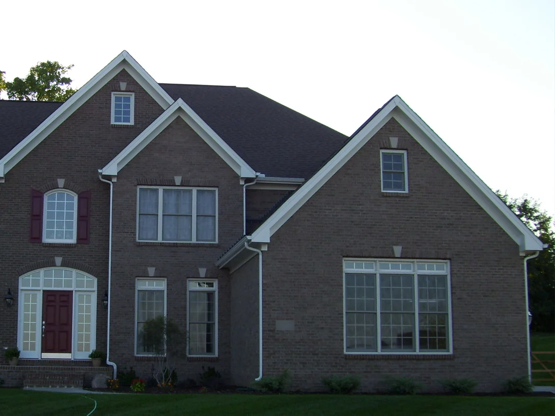 The front of the house the day after staining in 2007, two gables and the entry with the brick reading as one darker brown range, shot in evening light