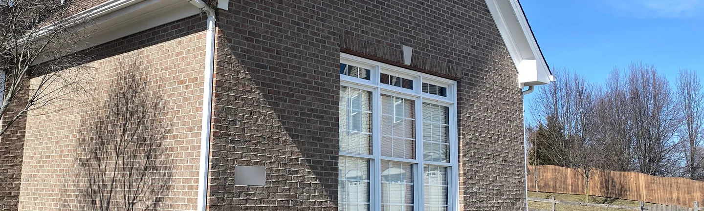 The gable end of the Mason, Ohio house in 2021, brown brick reading as one range around a tall white window