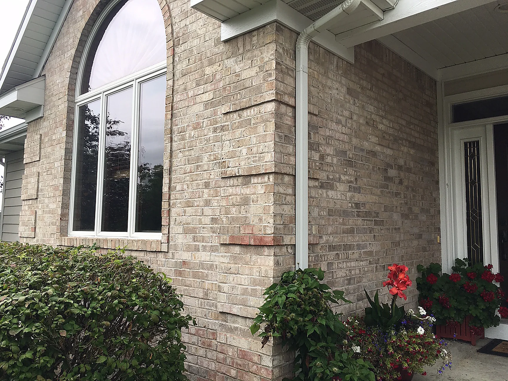 An outside corner of the house in 2019, the brick blended evenly across both faces beside the arched front window
