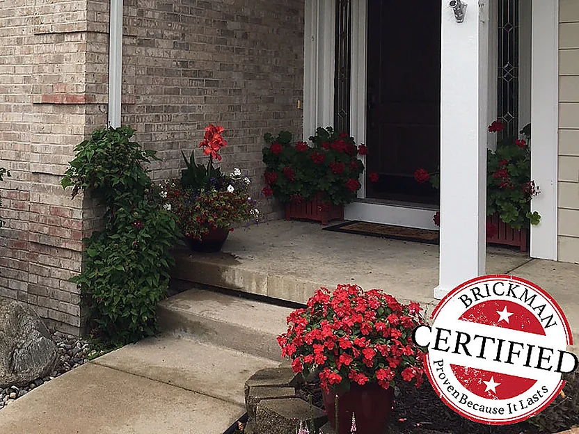 The front walk and covered entrance in 2019, the brick beside the door even in color, with the Brickman certification stamp on the frame
