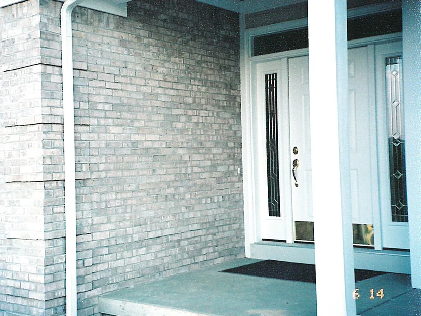 The covered entrance of the house in 2003, the brick around the front door blotched with grey and pale units