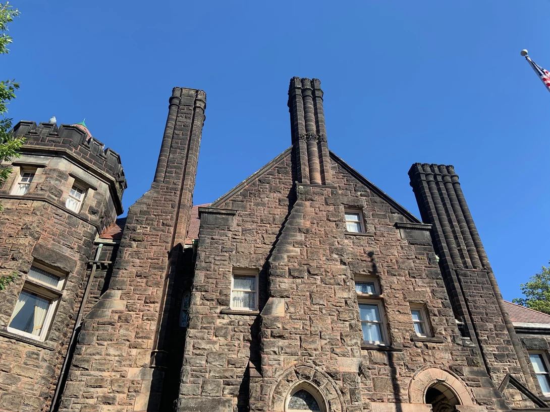 Clustered brick chimneys and a stone gable at Five Oaks seen from below against a clear sky in 2019