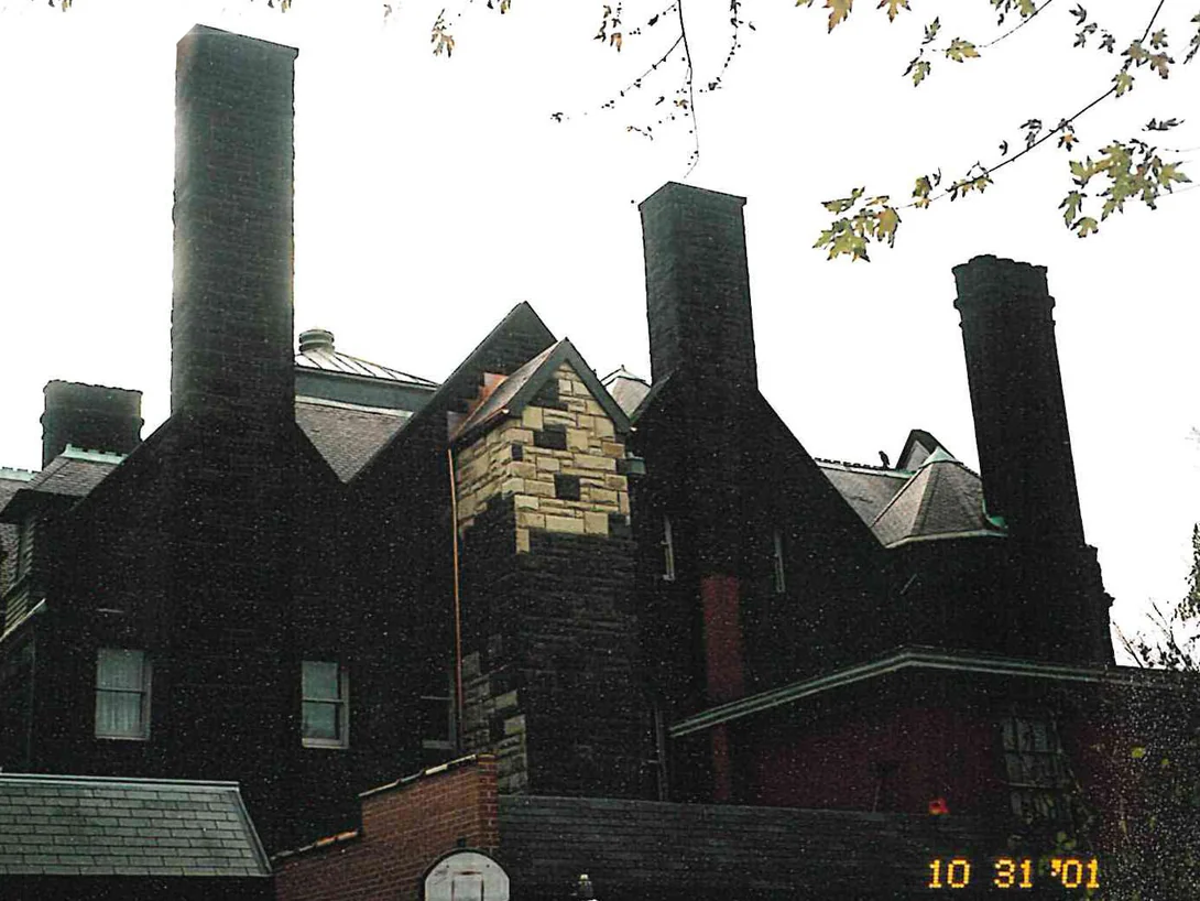The roofline of the house in 2001, chimneys and gables dark with weathering and one pale patch of replacement stone below the ridge