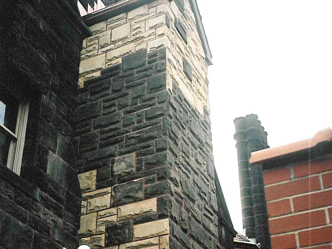A stair tower in 2001 with cream and tan replacement stone set into wall stone weathered almost black