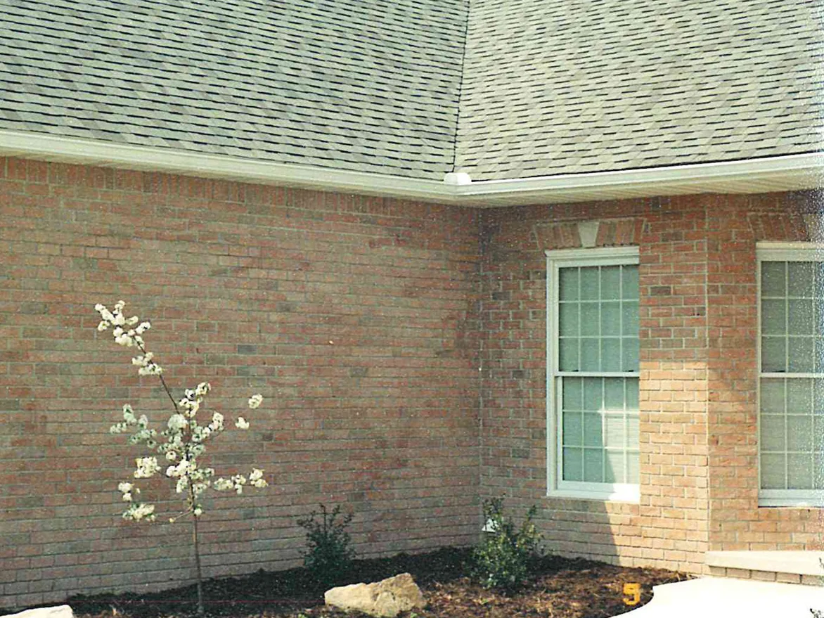 An outside corner of the brick house in 2001, the wall blotched and streaked in grey and dull red where the washing hit it
