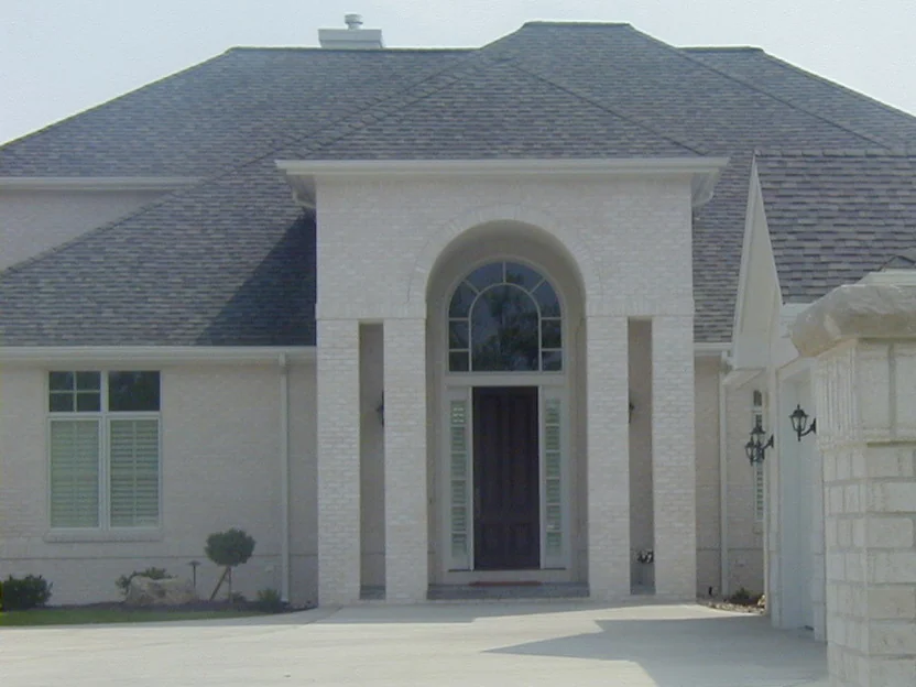 The front of the house in 2003 from the driveway, the hip roof and the entry portico in white brick with the ladder gone
