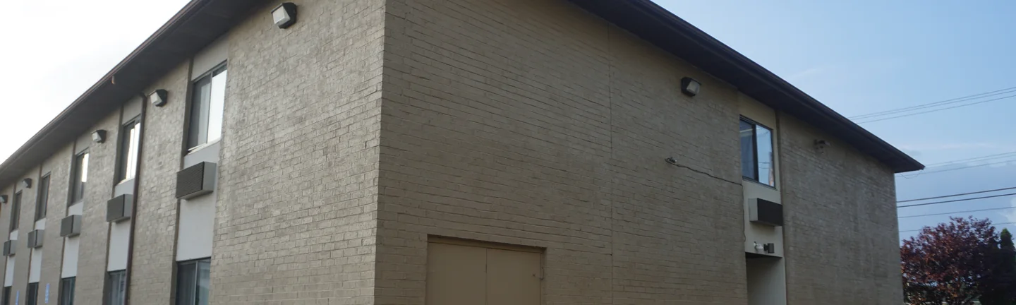 The corner of the Michigan hotel in 2019, both elevations under one flat coat of tan paint
