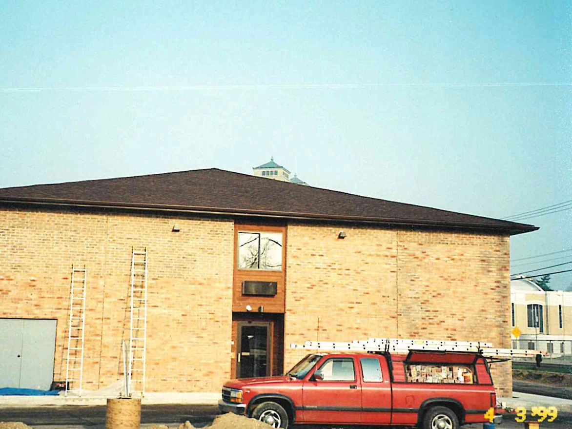 The gable end of the two-story hotel in 1999 with two extension ladders against the wall, its buff brick carrying patches of pink and orange