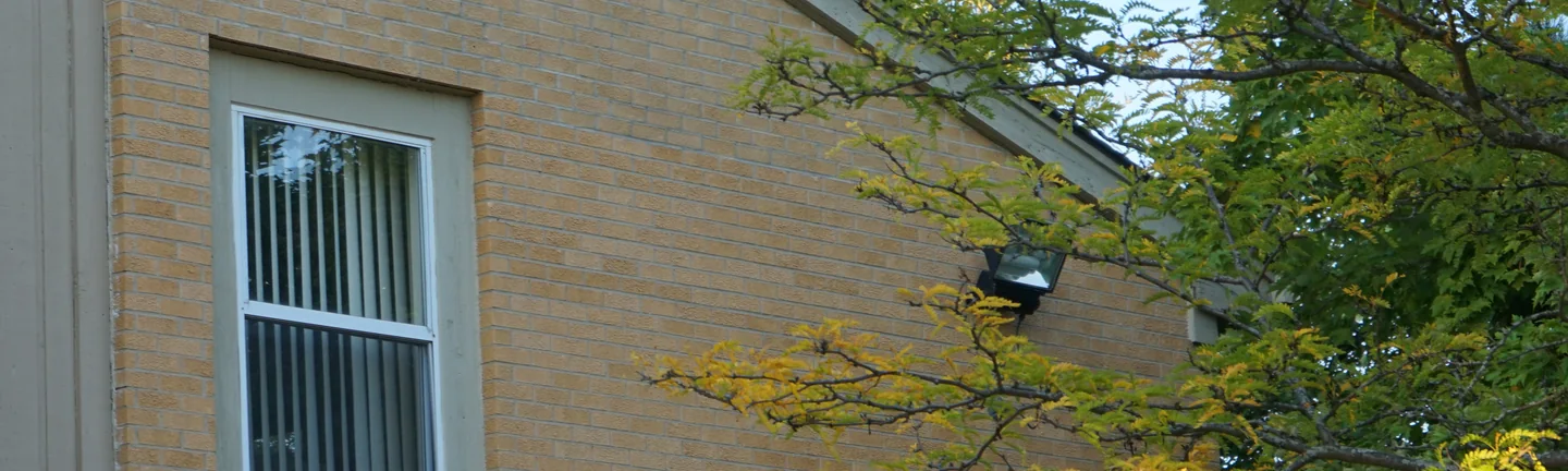 The buff brick gable end of a Michigan apartment block in 2019, reading as one even range under a long raking eaves line