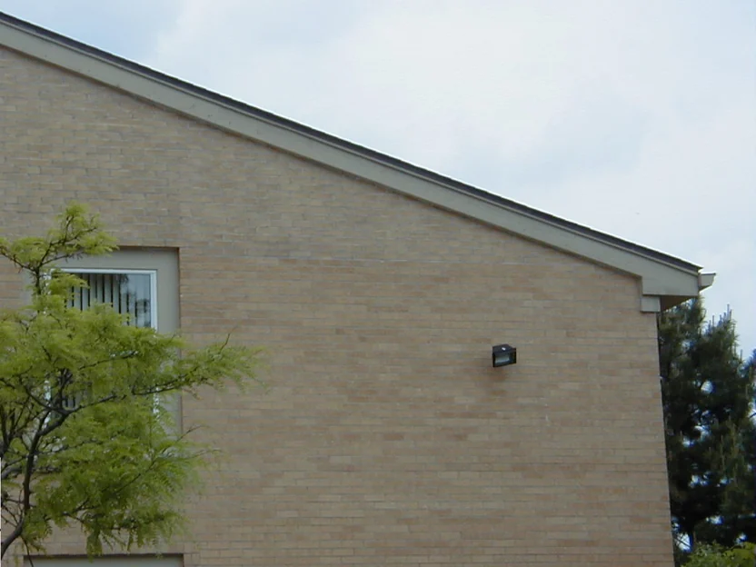 The same gable end after the 2000 work, the upper gable carried into the buff range of the wall below so the elevation reads as one color