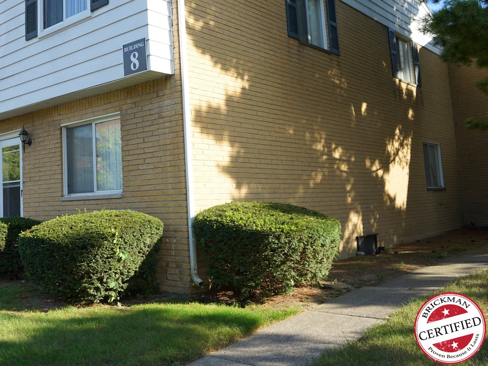 An outside corner of the apartment building in 2019, the buff brick reading as one even range across both elevations under white siding.