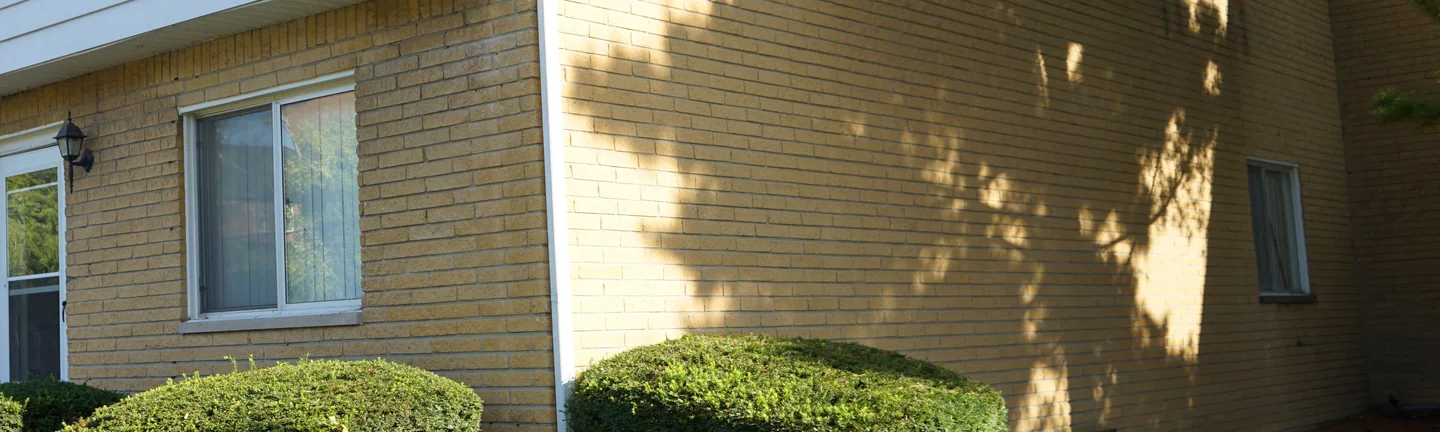 The buff brick of the apartment building in 2019, running unbroken around an outside corner