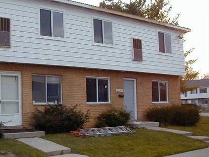 The front of the block in 2005 with a ladder lying on the lawn, the ground floor brick one even buff range under white siding
