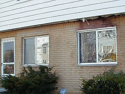 Fire damaged brick around a ground floor window in 2005, the units above the opening scorched dark and the soffit above them burnt through