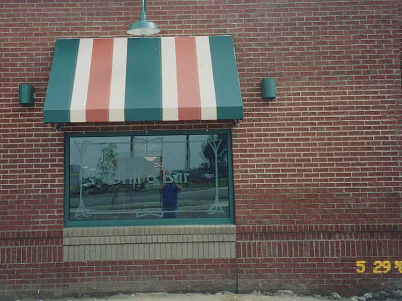A striped awning over a window in 2001, the brick around it running from red to a paler tan across the courses, with a camera date of 5/29/01 burned in at the corner