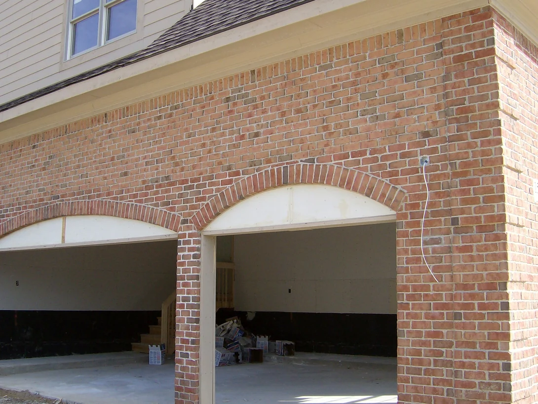 The garage wall of the house in 2007 with its brick arches turned and the openings not yet fitted, pale salmon and cream units scattered through the red range